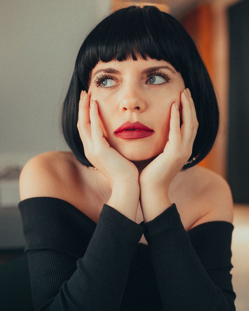 Mujer de carré negro con flequillo, labios rojos y top negro