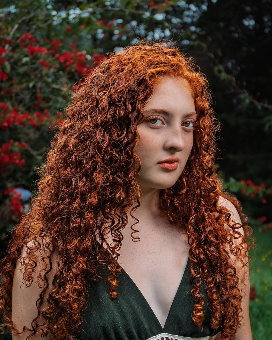 Mujer pelirroja de rulos en un jardín con flores