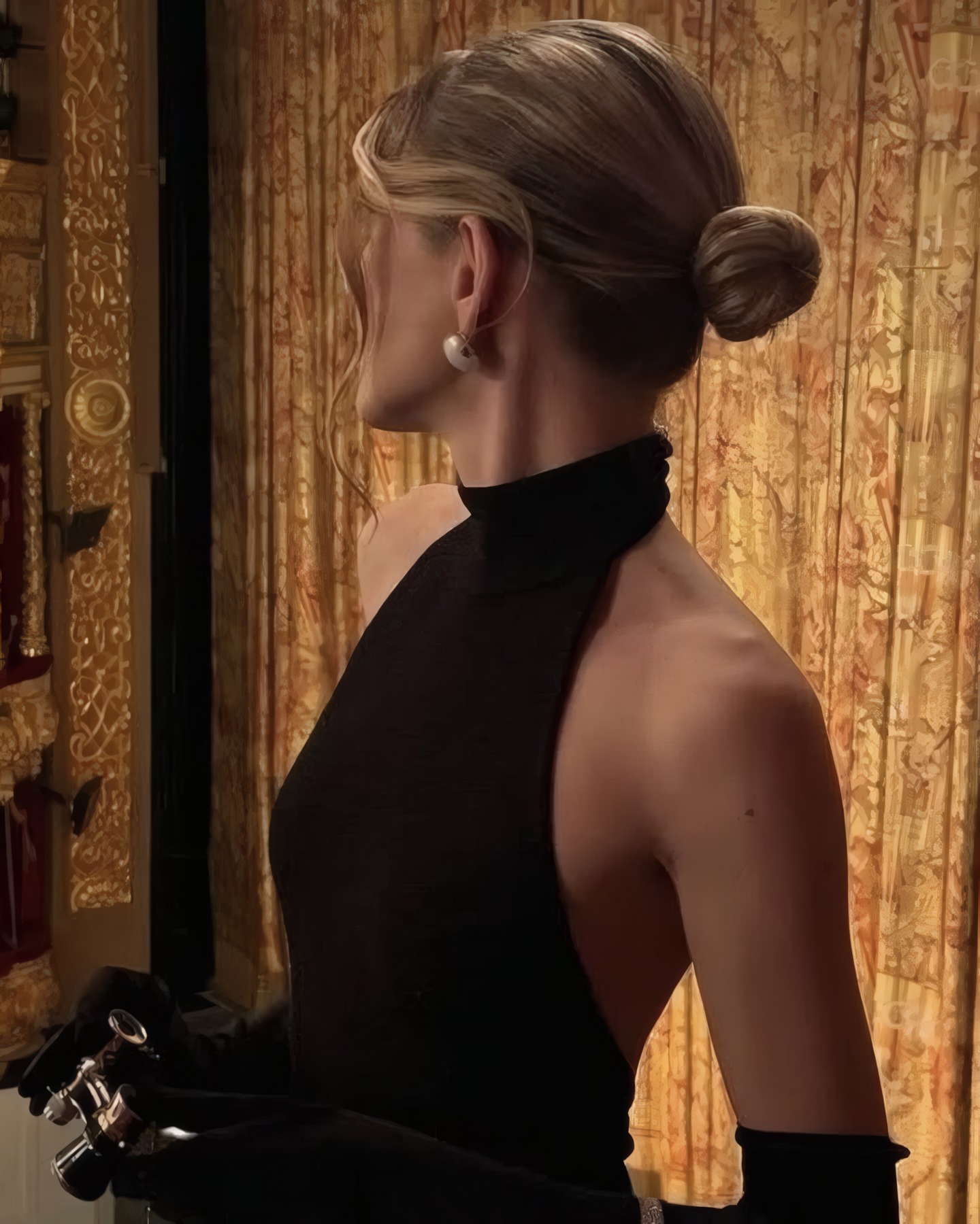Mujer de espaldas con vestido negro de cuello halter, guantes largos y rodete, en el palco de un teatro